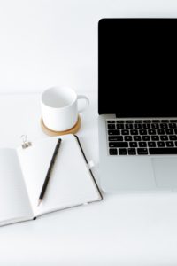 LMS, se muestra una laptop apagada, junto a una taza blanca a su izquierda.