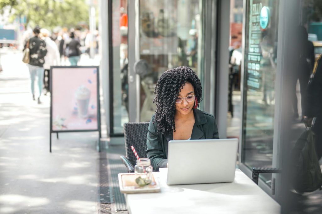 Capacitación en línea, mujer aprende desde una cafeteria en su dispositivo "laptop".