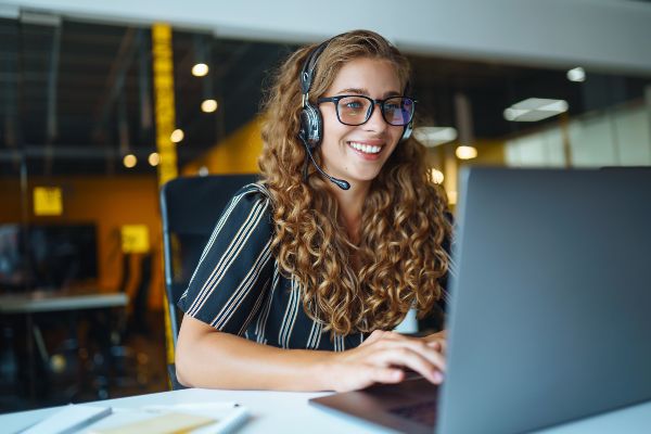 ALT imagen nueva: Catálogo de cursos, Mujer joven con auriculares usando una computadora portátil tomando sucurso de capacitación online