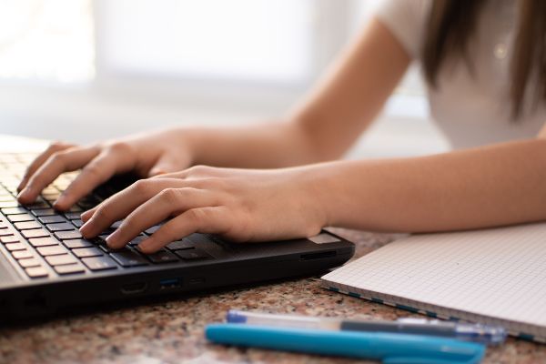 Cómo hacer un curso en línea, persona investigando en una laptop los contenidos de su curso online.