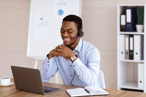 Cursos de capacitacion para empresas, Hombre negro feliz con formación en línea, interior de oficina.