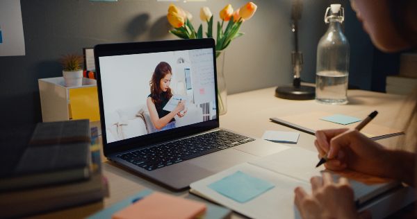 Plataformas de cursos; imagen de un joven tomando apuntes sobre el curso que está tomando a través de una plataforma digital.