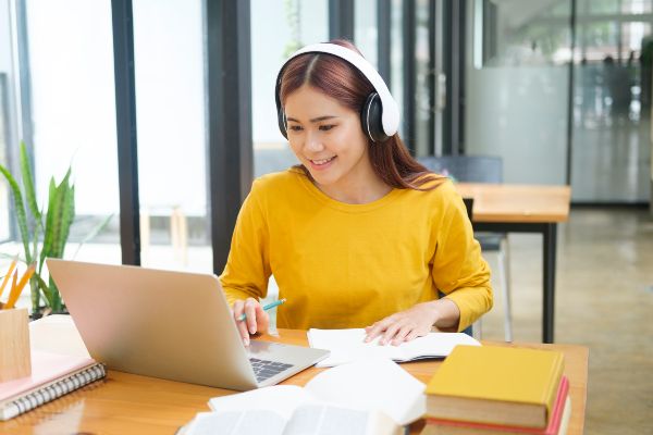 Que es gamificación, joven aprende en línea usando una laptop y escribiendo notas.