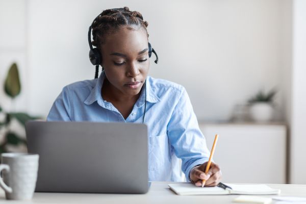 Tipos de LMS, joven afroamericana toma capacitación empresarial en una LMS desde una laptop.