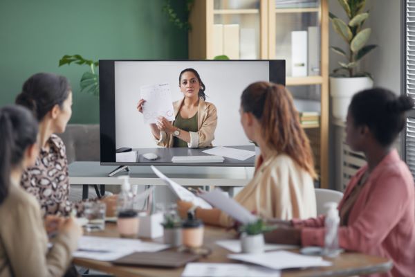 Coaches; imagen de múltiples mujeres en una sala de juntas recibiendo información detallada por parte de su coach para crecer en su negocio.