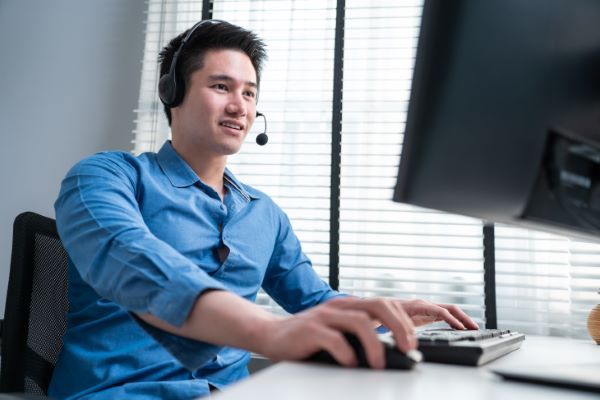 Plataformas para dar clases online; imagen de un joven tomando cursos y clases online en su computadora de escritorio y con auriculares.