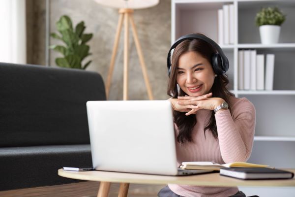 Plataformas para dar clases online; imagen de una joven feliz tomando sus clases de manera práctica en su computadora portátil.