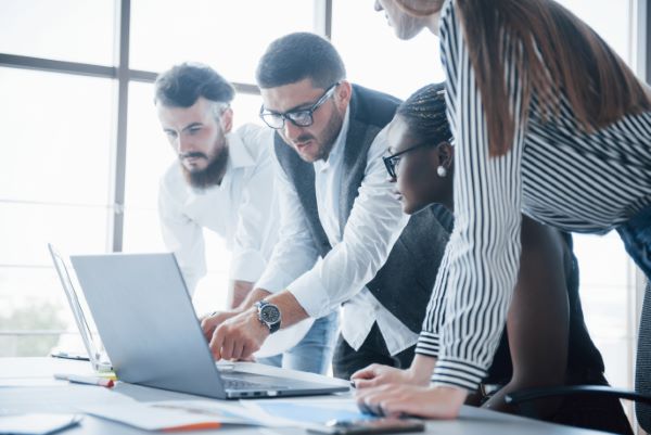 Tecnología educativa; imagen de un grupo de colaboradores de una empresa que esta haciendo uso de estrategias tecnológicas para un mejor conocimiento y desarrollo laboral a través de una computadora portátil.