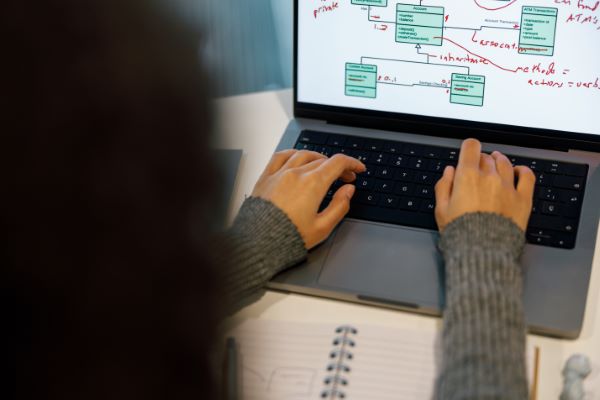 Tipos de LMS; imagen de una mujer escribiendo en su computadora portátil ejerciendo una serie de actividades de manera práctica gracias a los tipos de LMS.