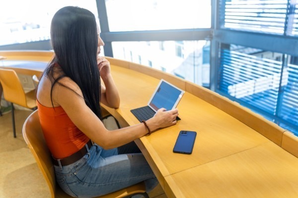 Educación continua; imagen de una joven usando una tablet para ampliar su conocimiento de manera práctica a través de cursos y estrategias educativas eficaces.